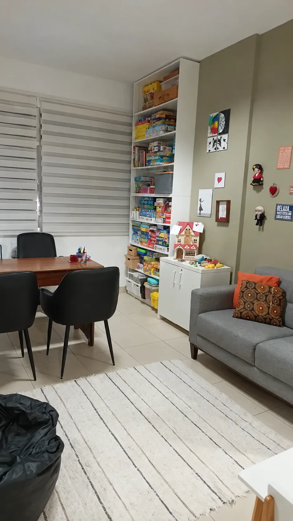 Sala de atendimento com mesa de trabalho, estante de jogos infantis e sofá